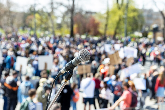 A mic in front of a crowd, illustrating sharing public opinions.