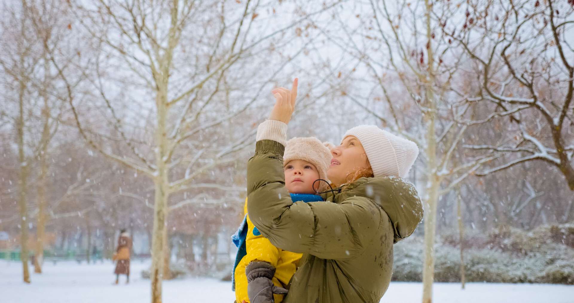 Mor og baby ser på snøfnugg som faller. 