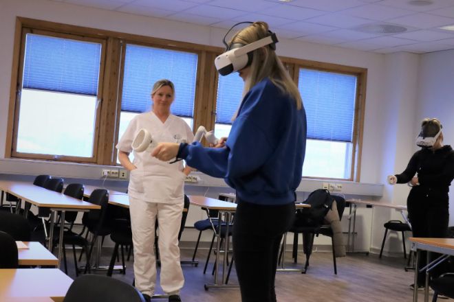 Student med VR-briller øver seg på pasientprosedyre- Faglærer ser på.