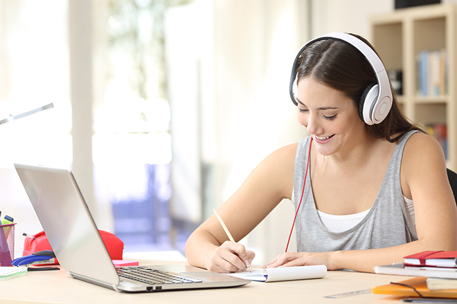 Bilde av kvinnelig student som ser på laptop med hodetelefoner