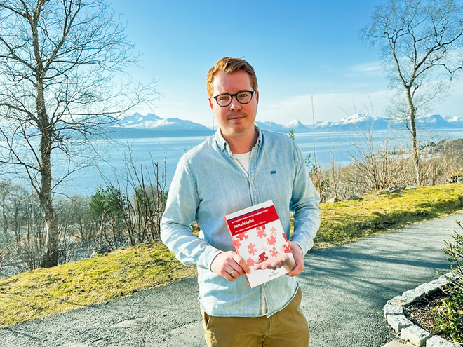 Erlend Vik utenfor Høgskolen i Molde med boka Helseledelse