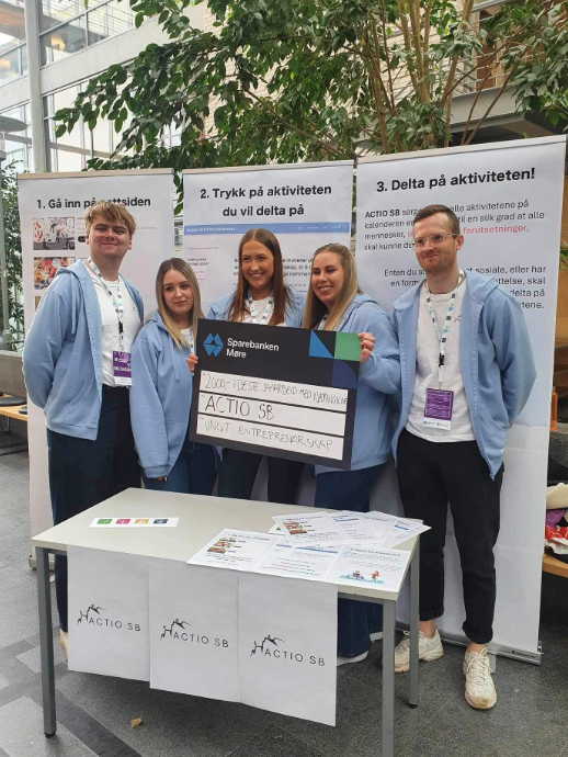 Foto av 5 studenter som holder en sjekk