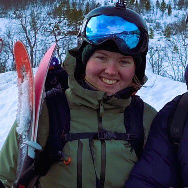 Solveig med skibriller og ski, utendørs, smilende. 